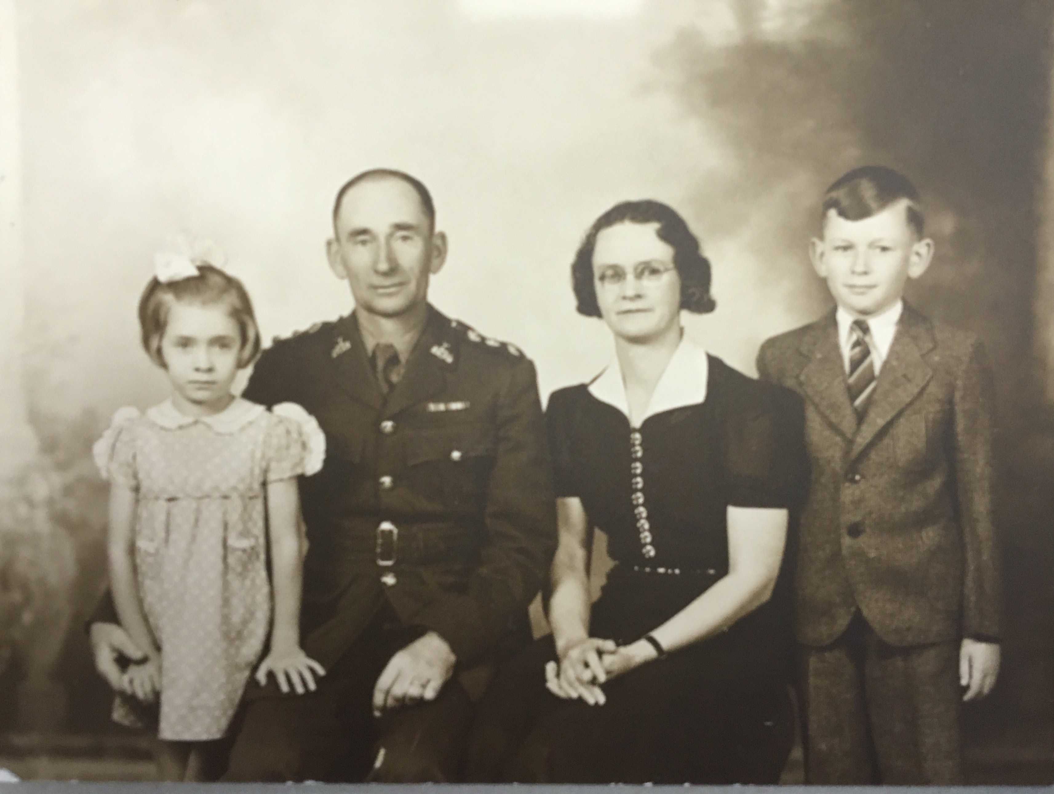 Black and white photograph. Archie, in uniform, has his right arm around daughter Margaret. Wife Grace is to his left, and son Francis is to her left.